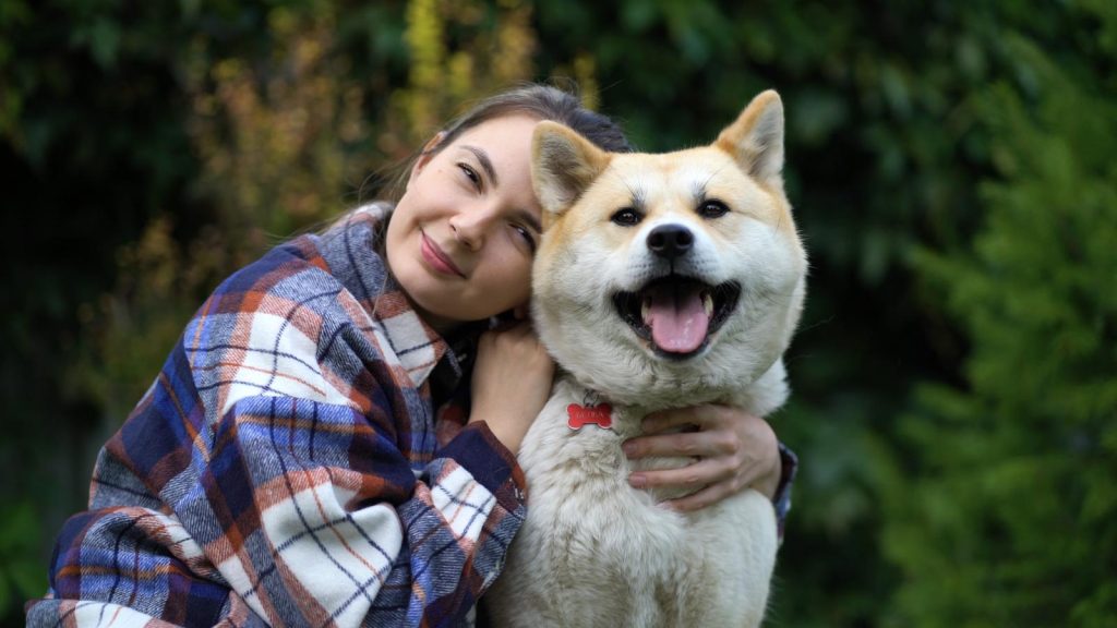 Una ragazza abbraccia il suo cane, entrambi guardano la camera