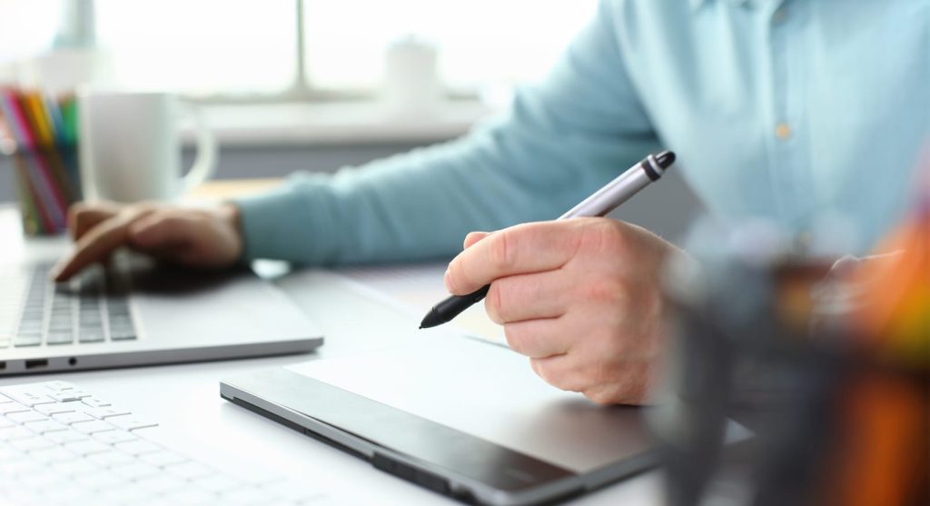 Un uomo seduto con una penna in mano si prepara a prendere appunti sul tablet