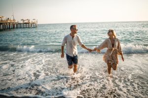 Un uomo e una donna si tengono per mano al mare mentre escono dall'acqua